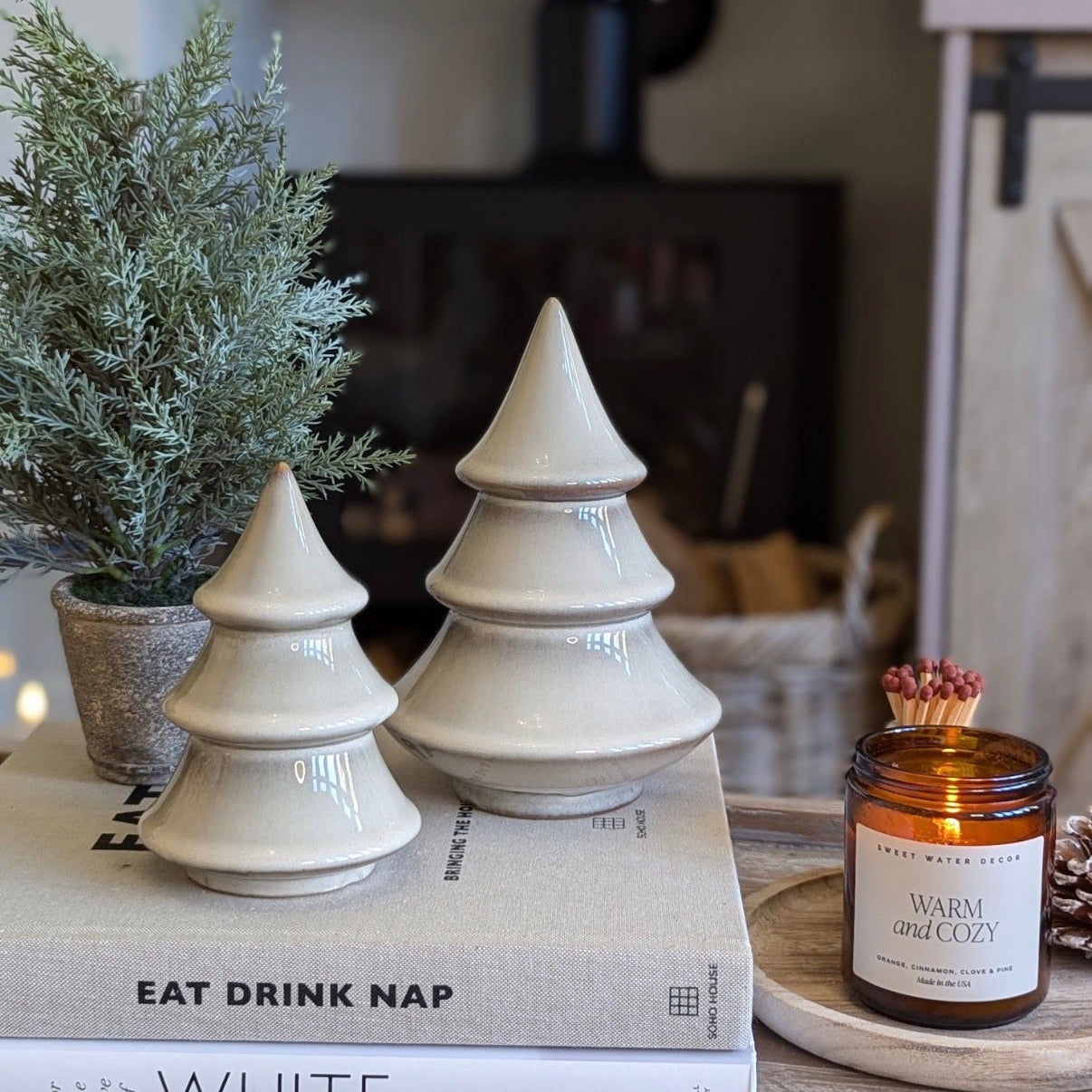 Decorative Christmas trees on books with a candle and plant in the background